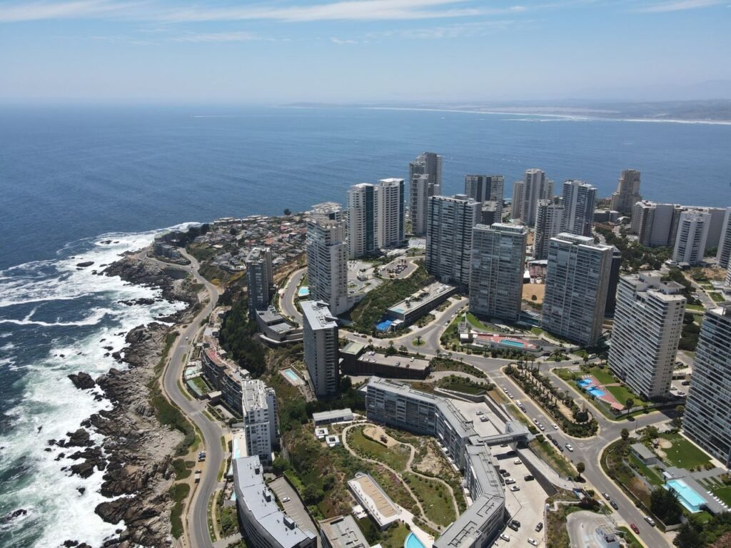 Aerial shot of modern high-rise buildings by the ocean in Viña del Mar, showcasing urban coastal architecture.