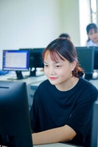 Asian student in a classroom engaging with computer for her studies, focused on learning.